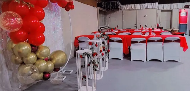 Arco de globos rojos y dorados sobre mesas con mantel rojo